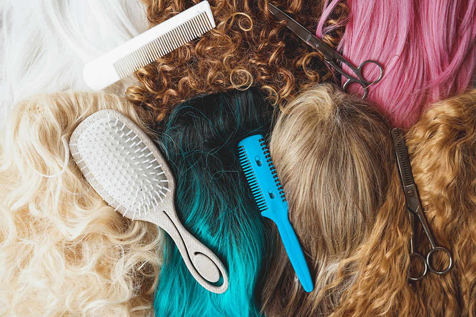 Image of assorted wigs of different styles and colors included dyed, curly and natural hair styles and hairdresser tools